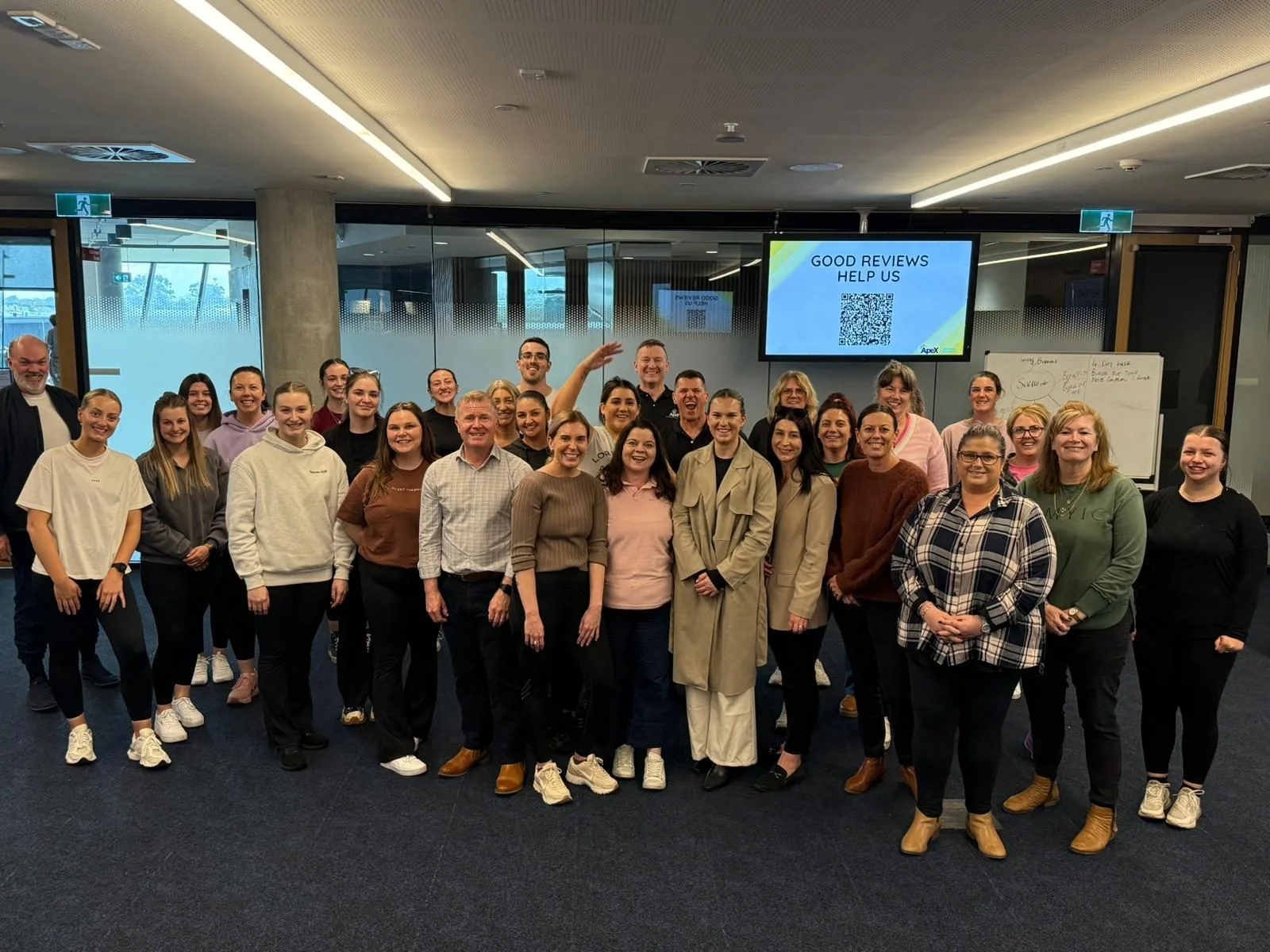 A large group of smiling participants and trainers at an Apex training session